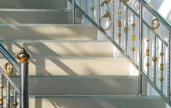 Light and shadow on surface of beige tile steps with stainless steel railing of vintage staircase