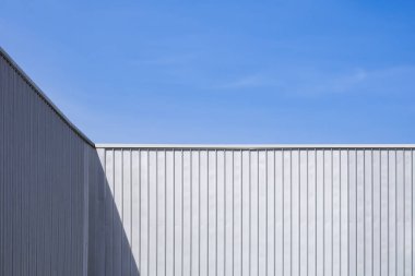 Oluklu Çelik Endüstriyel Depo Duvarı mavi gökyüzü arka planına karşı yüzey üzerinde ışık ve gölge