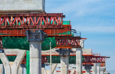 Precast segmental assembly box girder formwork on flyover foundation structure in road construction site against blue sky background