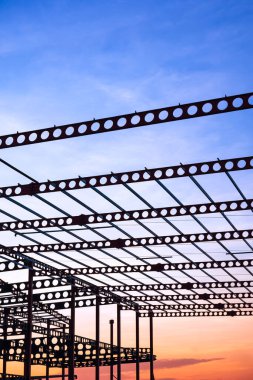 İnşaat alanındaki fabrika inşaatının metal castellated kiriş silueti günbatımı gökyüzü arka planı dikey çerçeve