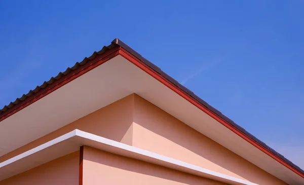 Shed roof of orange house in modern style against blue clear sky background in low angle and perspective side view