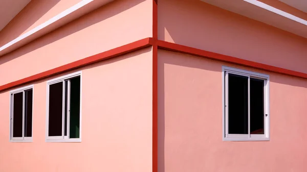 Exterior Architecture background of glass sliding windows on orange concrete wall of modern house with light and shadow on surface in Minimal style and symmetry view