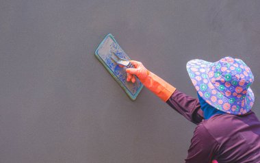 Kadın inşaat işçisinin yan görünüşü Çimentoyu Çitin Duvarına Cilalıyor, bakış açısı kopyalama alanı ile
