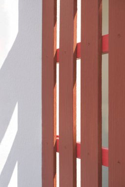 Kahverengi yapay ahşap çitlerin yüzeyindeki güneş ışığı ve gölge ve yeniden boyanmış beyaz beton direkler, ev yenileme ve geliştirme kavramları