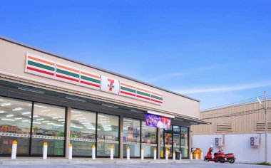 Samut Sakhon, Tayland - 31 Mart 2023: Müşteri hizmetleri otoparkı alanı, mavi gökyüzü arka planı, düşük açı ve perspektif kenarlı geniş 7-11 Apartman Binası