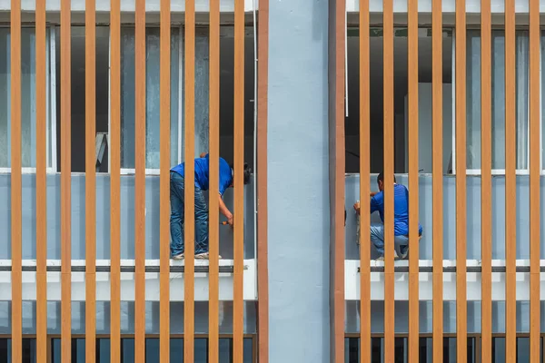 木架后面阳台上的两名建筑工人在外墙安装了供排水系统用的聚氯乙烯管道 — 图库照片