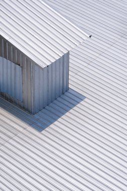 Güneş ışığı, bükülmüş metal çatıdaki küçük odanın yüzeyinde dikey çerçevede, sokak mimarisinin arka planında