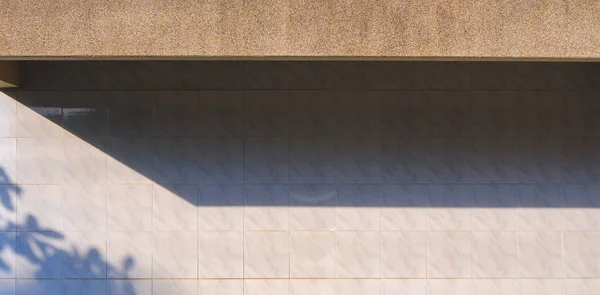 stock image Sunlight and shadow of exposed aggregate finish cobblestone awning on surface white tile wall background in panoramic view 