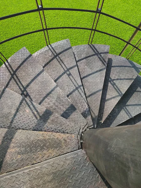 垂直フレームに緑の芝生と外側のスパイラル階段の黒い金属のステップ コピースペースとトップビュー — ストック写真