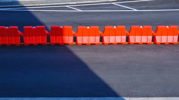 아스팔트 중앙에 주황색 플라스틱 장벽들 그림자가 표면에 주차장에 줄지어 — 스톡 사진