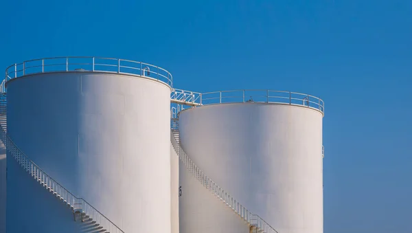 Group of white Storage Fuel Tanks in Oil Industrial area against blue sky background