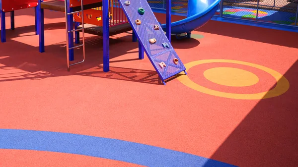 Colorful rubber floor with outdoor playground equipment at kindergarten school