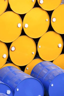 Dikey çerçevede 200 litre sarı ve mavi yağ varilleri yığılmış.