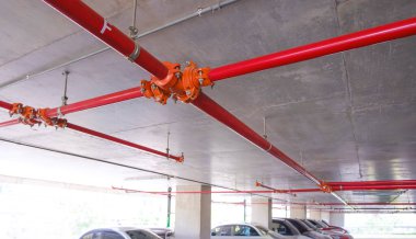 Otopark binasının içinde beton tavanda kırmızı yangın korumalı su boru hattı sistemi, düşük açı ve perspektif