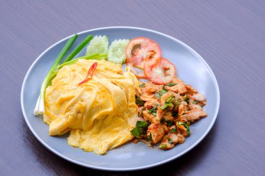 Baharatlı ızgara domuz salatası ve ahşap masadaki gri seramik tabakta sebzeli kremalı omlet.