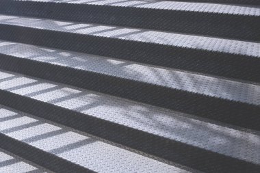 Açık hava metal merdiven arka planda ışık ve çelik basamaklarda gölge perspektif yan görünüm yüzeyinde