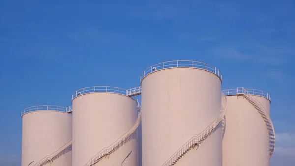 Group of Storage Fuel Tanks in Oil Industrial area against blue sky background in widescreen view