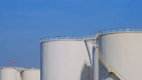 Group of white Storage Fuel Tanks in Petroleum Industrial area against blue sky background, perspective side view with copy space