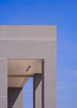 Modern binanın pürüzlü gri beton duvarında dikdörtgen ön kapı dikey çerçevede mavi gökyüzüne karşı. minimal dış mimari arkaplan tasarımı kavramı
