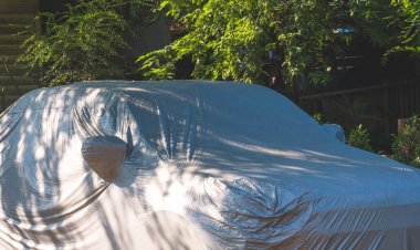 Evin dışındaki ağacın gölgesine park edilmiş koruyucu giysi altında bir araba.