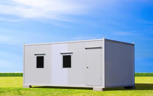Mavi gökyüzü arka planlı yeşil çimenlikte kiralık ve satılık beyaz mobil sandviç ofis konteynırı
