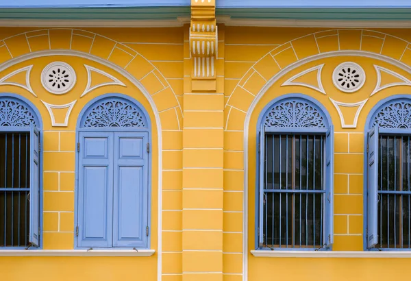 Klasik sarı bina arka planında mavi ahşap kemerli pencereler, sokak asgari stilde dış mimari