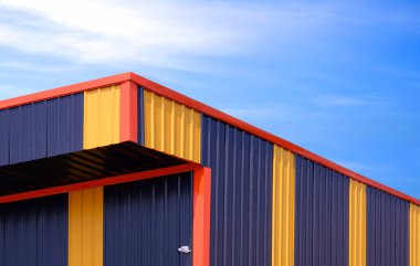 Alüminyum endüstriyel deponun sarı ve siyah renk modelleri mavi gökyüzü arkaplanı, düşük açı ve perspektif kenar görüşüne karşı