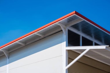 Çelik çatı ve ısı yalıtımı ile beyaz fiber beton duvardan yapılmış depo mavi gökyüzü arka planı, düşük açı ve bakış açısı