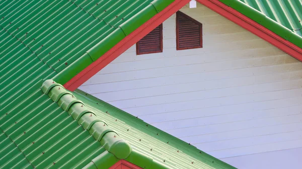 Green concrete tile polygonal roof and white wooden gable combination with 2 attic window of vintage house, high angle and perspective side view