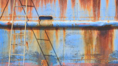 Geliştirme ve yenileme çalışmaları sırasında tersanede merdiveni olan eski bir deniz gemisinin paslı metal gövdesi.