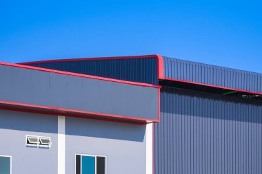 Metal deponun yanındaki endüstriyel ofis binası mavi berrak gökyüzü arkaplanına karşı, kopyalama alanı ile yan görünüm