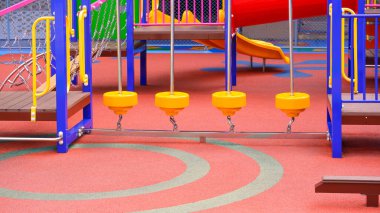 Bir grup renkli tırmanma ekipmanı. Kreşteki çocuk parkında, kauçuk zeminde denge köprüsü var.