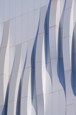 Modern binanın gri alüminyum kompozit duvar dikey dekorasyonunun yüzeyinde ışık ve gölge olan boyut eğrisi çizgileri, minimal dış mimari arka plan
