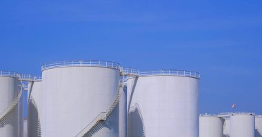 Petrol endüstriyel alanındaki beyaz depolama tankları mavi berrak gökyüzü arka planına karşı