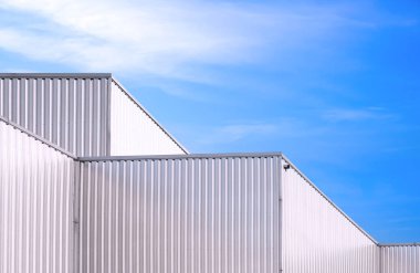 Alüminyum kıvrımlı çelik duvarın geometrik modeli endüstriyel fabrika binalarının mavi gökyüzü arka planı, düşük açı ve yan bakış açısına karşı