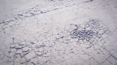 Kötü hasar görmüş beton sokak yüzeyinde çatlaklar ve kırık doku var.