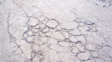 Kötü hasar görmüş beton sokak yüzeyinde çatlaklar ve kırık doku var.