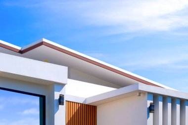 Beyaz beton duvarın geometrik desenli yüzeyinde güneş ışığı alan modern ev binası mavi gökyüzü arka planı, düşük açı ve bakış açısı