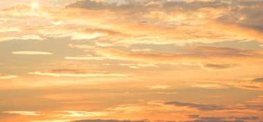 Günbatımı gökyüzü, sarı ve turuncu güneş ışığı bulutlarıyla altın gökyüzü arka planında panoramik manzarayla