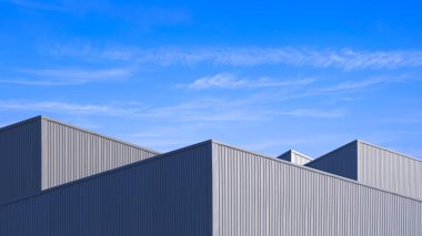Geometrik endüstriyel fabrika binaları, gri alüminyum yüzey üzerinde güneş ışığı ve gölgesi olan mavi gökyüzü arka planına karşı en düşük açılı, düşük açılı ve perspektifli çelik duvar.