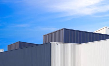 Mavi gökyüzü arkaplanına karşı gri ve beyaz alüminyum duvarlı modern endüstriyel fabrika binaları, kopya alanı ile düşük açı ve perspektif yan görünümü