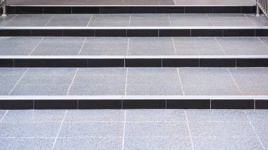 Açık hava tuvaletinin rampa bölgesinde yükseltilmiş gri fayans adımları.