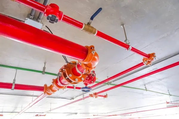 Otopark binasının içindeki beton tavanda kırmızı yangın korumalı su boru hattı sistemi, düşük açı ve seçici odak noktası