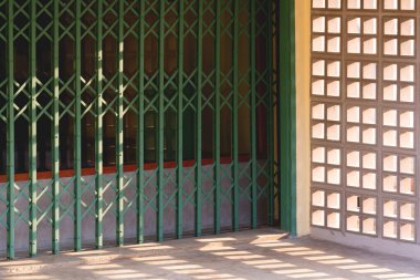 Esnetilmiş çelik kapı ve kare beton havalandırma bloğu. Yüzeyinde ışık ve gölge olan klasik kahve dükkanının duvarı.