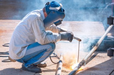 Kaynakçı inşaat alanındaki inşaat yapısını geliştirmek için galvanize çelik boru yapıyor.