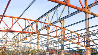 İnşaat alanındaki sanayi binasının tepesine, düşük açılı ve perspektifli yan görüş için zemindeki eğri metal kirişler yapısı