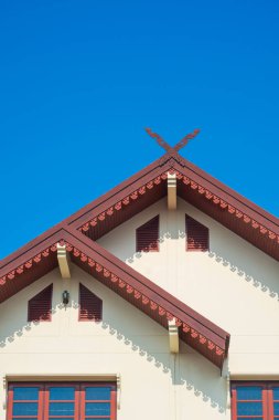 Gable çatısının üst kısmında mavi gökyüzü arka planına karşı ahşap süslemeli klasik ev Kalae, Tayland Lanna mimarisi tarzıdır.