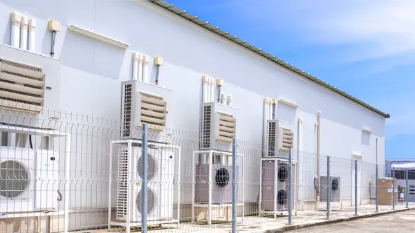 HVAC Sisteminde havalandırma donanımlı bir grup klima kompresörü mavi gökyüzü arkaplanına karşı arka taraftaki market duvarlarında boru hatları var.