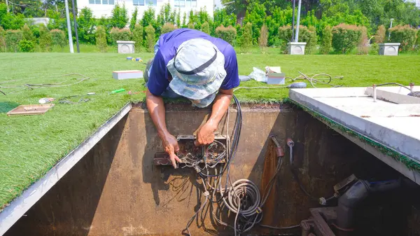 Teknisyen göletin içindeki atık su arıtma sisteminin elektrik ekipmanlarını tamir ediyor. 
