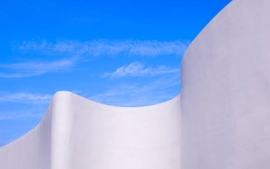 Modern binanın beyaz eğimli beton dış duvarı mavi gökyüzü arka planı, soyut mimari dekorasyon arka planı, düşük açı ve perspektif yan görünümü karşısında minimal tarzda